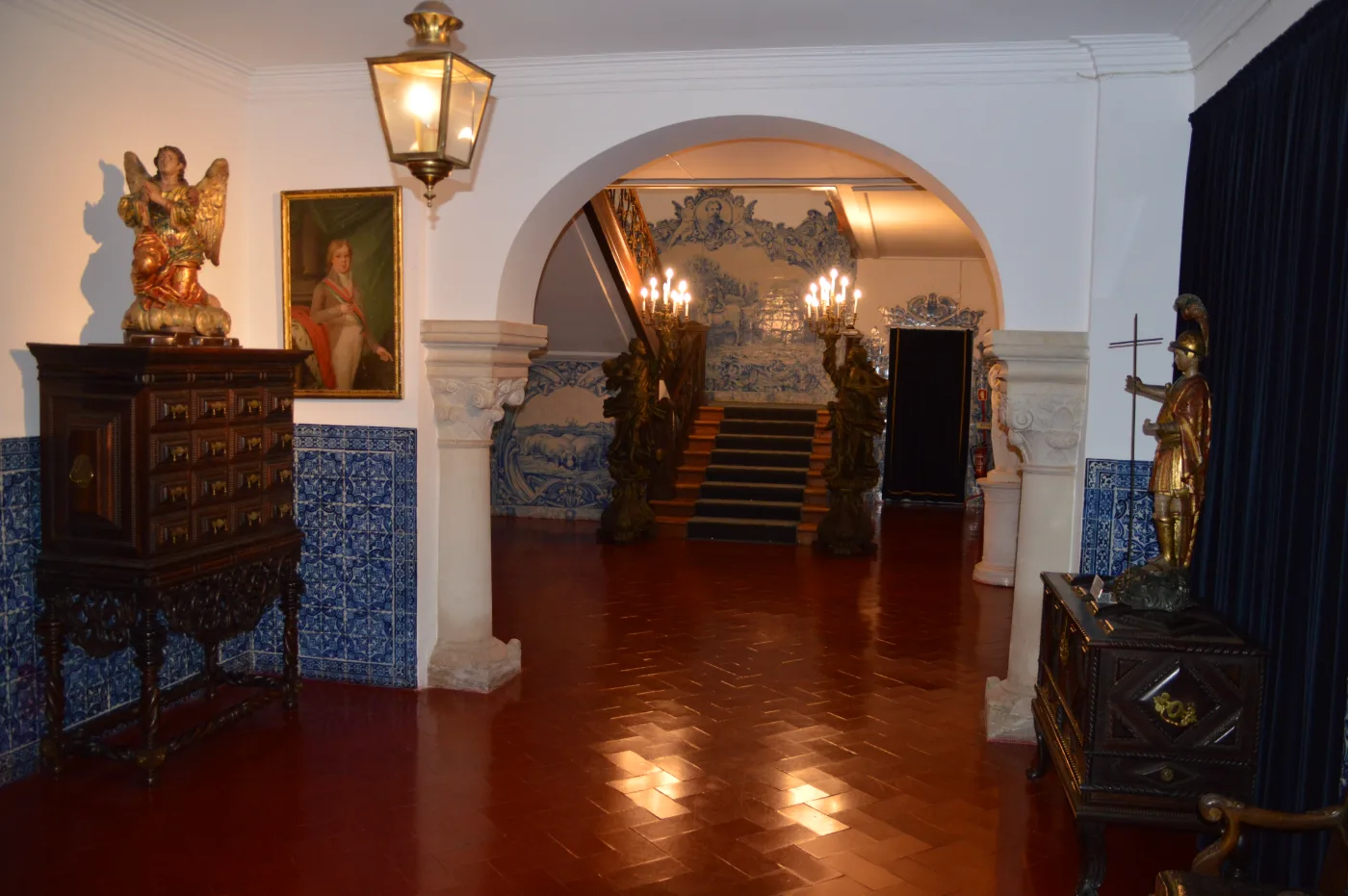 Sala da Casa dos Patudos revestida a azulejos azuis com retratos de família a óleo, pavimento de madeira e tapete de Arraiolos